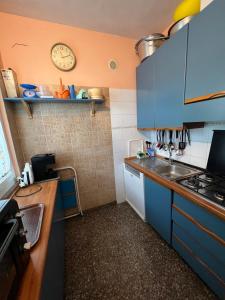 a kitchen with blue cabinets and a clock on the wall at Casa al mare con giardino vicino a Roma in Torvaianica