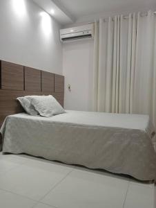 a bedroom with a large bed with a white blanket at Confortável apartamento in Goiânia