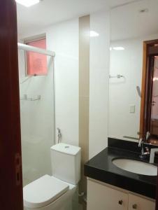 Baño blanco con aseo y lavamanos en Confortável apartamento, en Goiânia