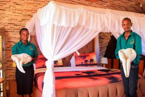 two men are standing in front of a bed at Little Amanya Camp Amboseli in Amboseli