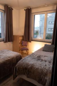 a bedroom with two beds and a chair and windows at L'Albatros in Le Tréport