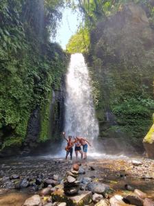 two people standing in front of a waterfall at Bunga Maliq Bungalow Lombok in Tetebatu