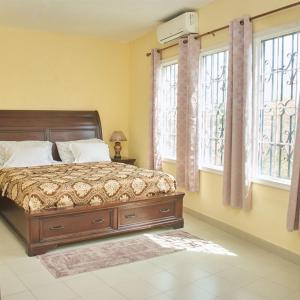 a bedroom with a bed and two windows at Résidence SOTOUR, Liberté 6 Extension VDN - Newly Renovated Luxury 1 , 2, 3 and 4- Bedroom Apartment-Condos, Living Room, Kitchen and Balcony in Dakar