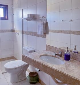 a white bathroom with a toilet and a sink at Porto Serra Mar Flats Praia de Sibaúma- Pipa in Tibau do Sul