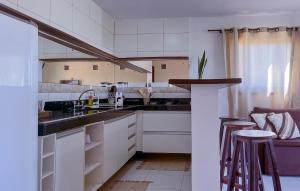 a kitchen with white cabinets and a sink and stools at Porto Serra Mar Flats Praia de Sibaúma- Pipa in Tibau do Sul