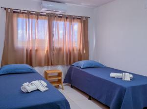 a bedroom with two beds with blue sheets and a window at Porto Serra Mar Flats Praia de Sibaúma- Pipa in Tibau do Sul