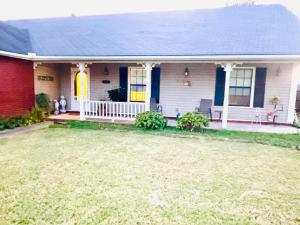 a white house with a yellow door and a yard at Cozy house centrally located close to everything in NWA in Springdale