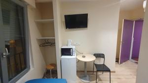 a small room with a small table and a tv on the wall at Hotel le Privilege in La Courneuve