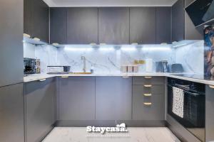 una cocina con armarios grises y encimeras de mármol en Luxury 2bdr Flat With Canal View & Free Parking, en Mánchester
