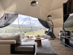 a living room with a couch and a large window at Glamping Dome - Pinot in Cromwell