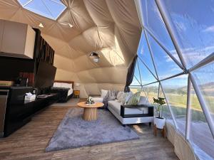 a living room in a tent with a couch and a table at Glamping Dome - Pinot in Cromwell