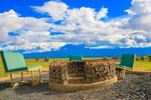 2 chaises assises à côté d'une cheminée en pierre dans l'établissement Little Amanya Camp, à Amboseli