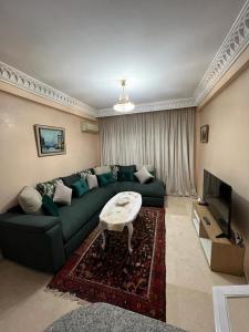 a living room with a green couch and a tv at Luxury apartment 3 in the heart of Gueliz, Wifi, Pool in Marrakech