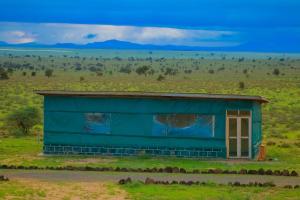 a blue building in the middle of a field at Little Amanya Camp in Amboseli