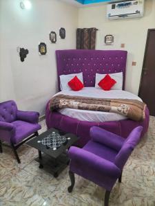 a bedroom with a purple bed and two purple chairs at NTP Hotel in Lahore