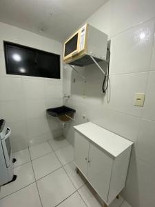 - une petite salle de bains blanche avec un four micro-ondes sur le mur dans l'établissement Temporada CG - Apartamento no Alto Branco, à Campina Grande
