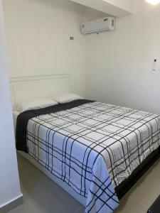 een slaapkamer met een bed met een blauwe en witte deken bij Plataview Apartahotel 3B in Monte Plata