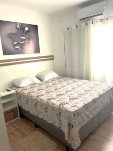 um quarto com uma cama com uma colcha florida em Apartamento Guaruja Enseada no Guarujá