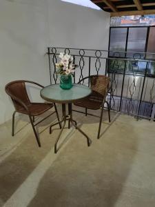 a table with two chairs and a vase with flowers on it at Casa petirrojo - habitaciones en Pátzcuaro in Pátzcuaro