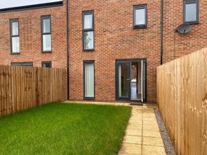 a brick house with a fence and a yard at STAN LUXURY HOME in Manchester