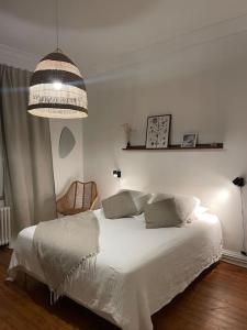um quarto com uma cama branca e um lustre em Grand appartement charmant à 10 min de Lille em Tourcoing