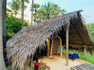 a straw hut with a thatched roof and palm trees at Delft Village Stay in Delft East