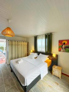 ein Schlafzimmer mit einem großen weißen Bett in einem Zimmer in der Unterkunft Villa Sweet Caraïbes, vue mer, jacuzzi in Les Trois-Îlets