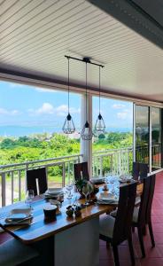 a dining room with a table and a large window at Villa Sweet Caraïbes, vue mer, jacuzzi in Les Trois-Îlets