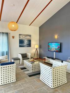 a living room with white furniture and a flat screen tv at Villa Sweet Caraïbes, vue mer, jacuzzi in Les Trois-Îlets