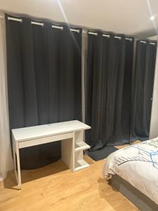 una mesa blanca en una habitación con cortinas negras en Self-contained en-suite room in Wembley, en Londres