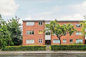 um edifício de tijolos com uma árvore em frente em Lovely Studio Flat in Wimbledon w/ Free Parking em Londres