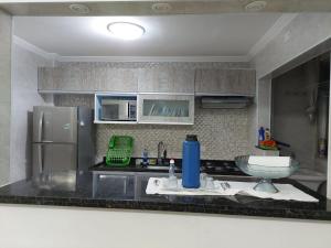 uma cozinha com um lavatório e um frigorífico em Cantinho de vó - Praia Grande - Aviação em Solemar
