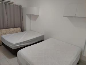 Duas camas num pequeno quarto com paredes brancas em Cantinho de vó - Praia Grande - Aviação em Solemar