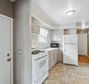 a white kitchen with a stove and a refrigerator at Modern River Retreat near airport, hospitals, businesses 