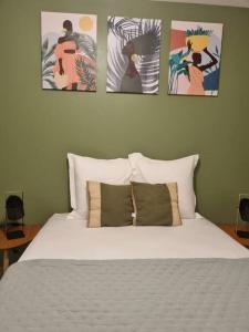 1 dormitorio con 1 cama con 3 cuadros en la pared en T3 ZAC HIBISCUS, en Cayenne