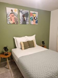 1 cama en un dormitorio con cuadros en la pared en T3 ZAC HIBISCUS, en Cayenne