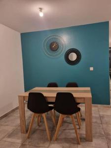 mesa de comedor con sillas y pared azul en T3 ZAC HIBISCUS, en Cayenne