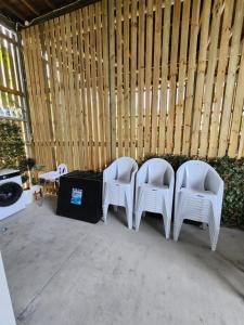OXLEY Private Heated Mineral Pool & Private Home في بريزبين: مجموعة من أربعة كراسي بيضاء تجلس أمام الجدار