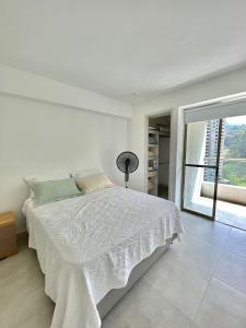 een witte slaapkamer met een bed en een groot raam bij Hermoso y acogedor loft cerca Estación Estrella in Sabaneta