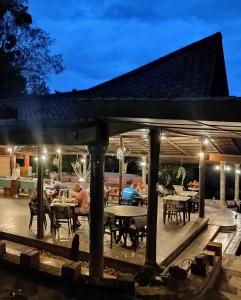 un patio con mesas y sillas por la noche en Balai Serama Guesthouse en Kuala Tahan