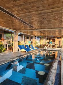 a swimming pool with blue chairs and a wooden ceiling at Nusa View in Nusa Lembongan