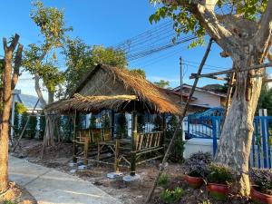 uma mesa e cadeiras debaixo de um guarda-sol de palha em Piyaporn Guesthouse em Khon Kaen