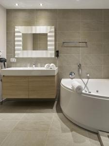 ein Badezimmer mit Badewanne, Waschbecken und Spiegel in der Unterkunft Romantik Parkhotel het Gulpdal in Slenaken