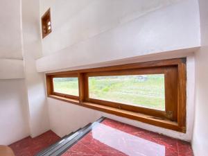 ein Fenster in der Ecke eines Zimmers mit rotem Boden in der Unterkunft nDalem Abhirama in Ngaglik