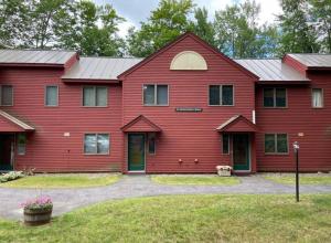 a red house with a red roof at Cozy Condo in the Woods (5 mins to Loon Mountain) in Lincoln