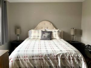a bedroom with a bed with a plaid comforter at Cozy Condo in the Woods (5 mins to Loon Mountain) in Lincoln