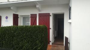 a white building with a red door and a hedge at Acogedor apartamento entre España y Francia. in Hendaye