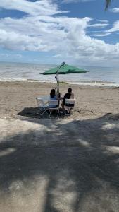 dos personas sentadas en sillas bajo una sombrilla en la playa en Nahas Beach Resort, 