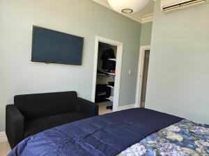 a bedroom with a bed and a flat screen tv on the wall at Aspiring Villa Apartment in Christchurch