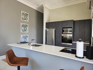 a kitchen with a counter with a sink and a chair at Aspiring Villa Apartment in Christchurch
